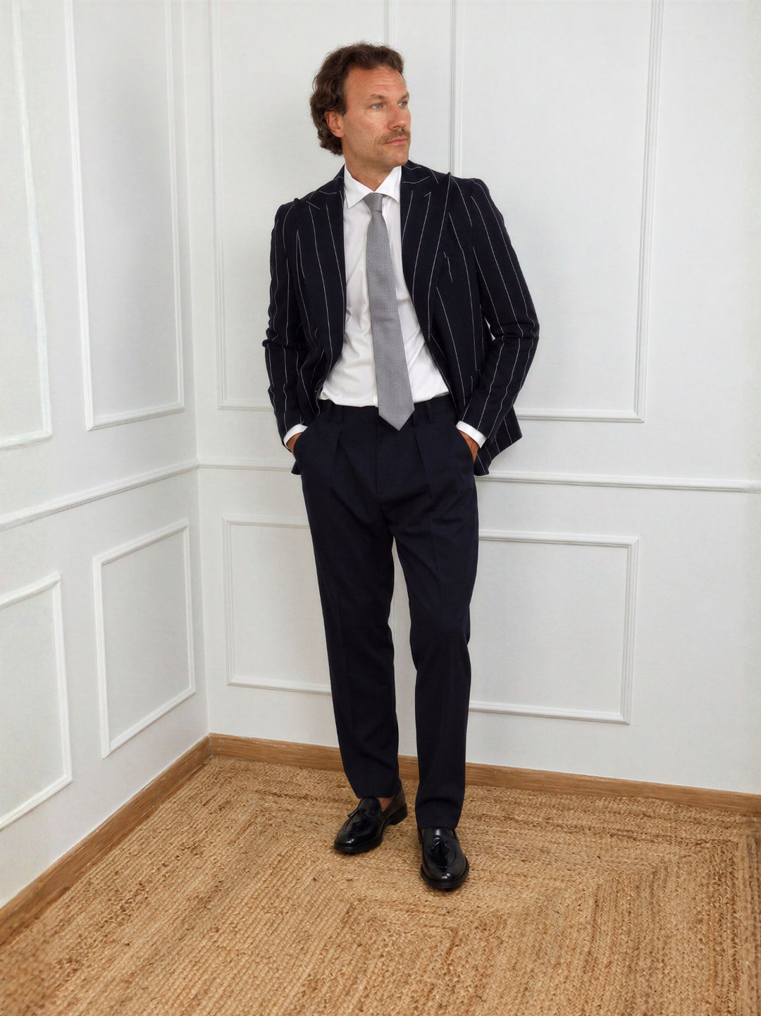 Completo uomo con giacca rigata scura, camicia bianca, cravatta nera e pantaloni scuri